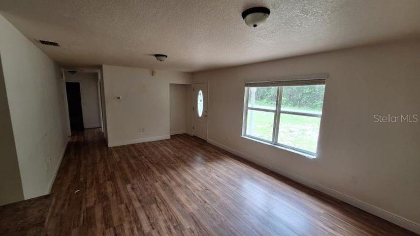 An open-concept living area features wood-look flooring, light gray walls, and a kitchen peninsula — 788 N CHARLES AVENUE, INVERNESS, FL