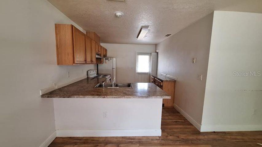An empty living room features light gray walls, wood-look flooring, a front door, and a window — 788 N CHARLES AVENUE, INVERNESS, FL