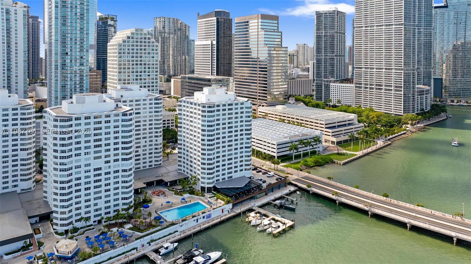 An aerial view shows waterfront residential buildings with a pool, boat slips, and a bridge — 801 Brickell Bay Dr # 361, Miami FL 33131, MIAMI, FL