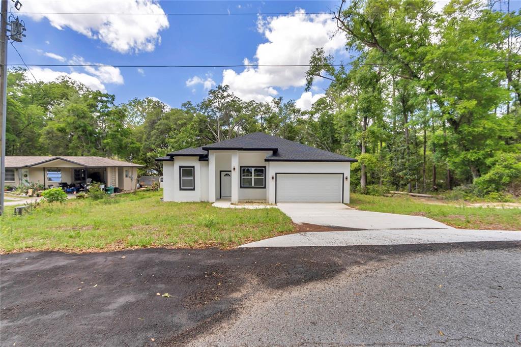 A newly constructed white single-story house with a black roof and an attached garage — 4592 SW CHANNEL HEIGHTS COURT, DUNNELLON, FL