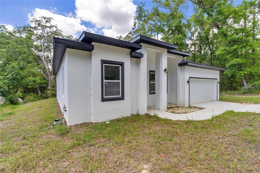 A white, modern single-story house with a black roof and an attached garage — 4592 SW CHANNEL HEIGHTS COURT, DUNNELLON, FL