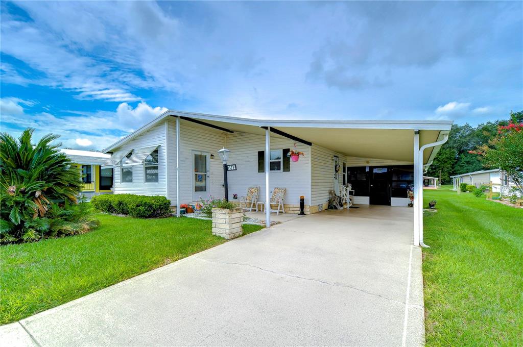 A white mobile home features a concrete driveway, a carport, and a small front yard — 3843 DAMIAN DRIVE, ZEPHYRHILLS, FL