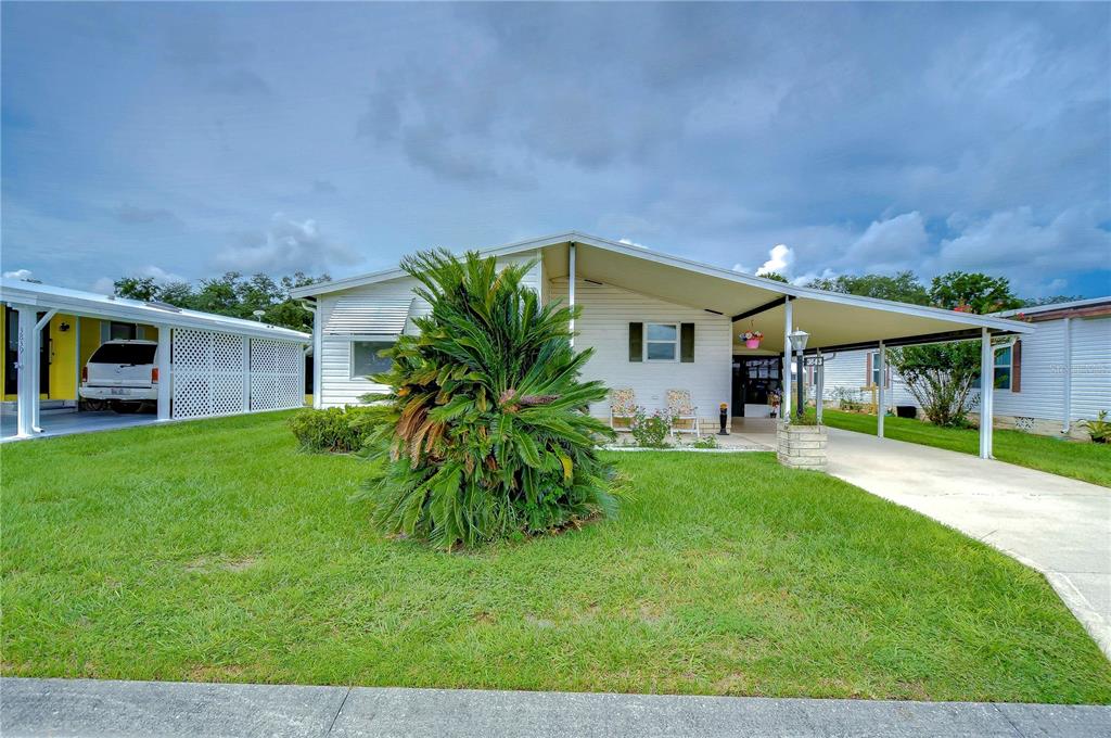 A single-story mobile home with a large sago palm in the front yard — 3843 DAMIAN DRIVE, ZEPHYRHILLS, FL