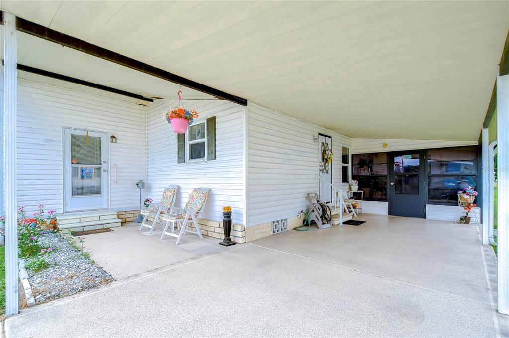A covered concrete carport and patio area attached to the side of a white house — 3843 DAMIAN DRIVE, ZEPHYRHILLS, FL