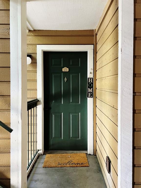 A green front door with a "208" sign and a welcome mat on a porch — 4225 THORNBRIAR LANE UNIT 208, ORLANDO, FL