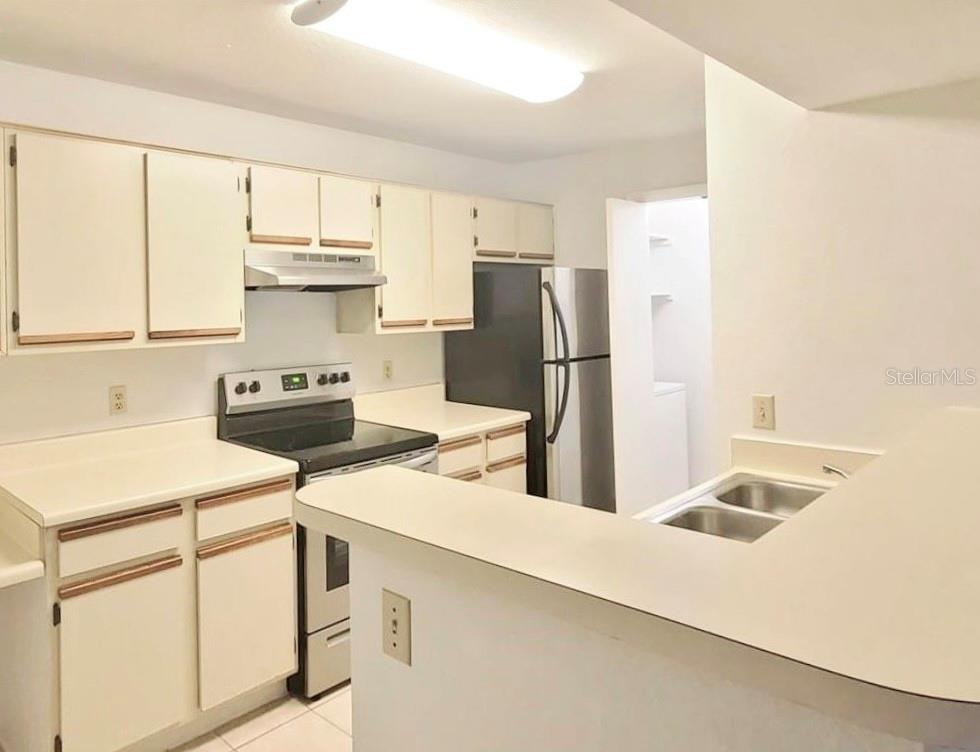 A kitchen with white cabinets, laminate countertops, and stainless steel appliances — 4225 THORNBRIAR LANE UNIT 208, ORLANDO, FL