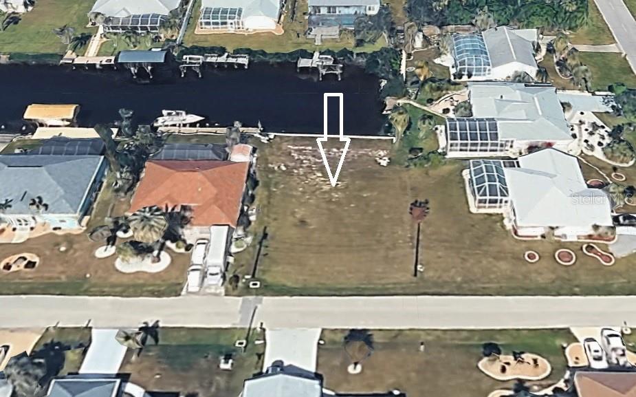 An aerial view shows a vacant waterfront lot situated between two existing residential homes — 19262 PINE BLUFF COURT, PORT CHARLOTTE, FL