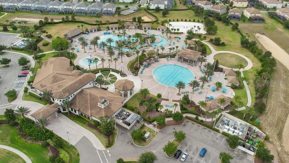 An aerial view shows a community clubhouse with multiple swimming pools, palm trees, and parking — 1051 QUAKER RIDGE LANE, DAVENPORT, FL