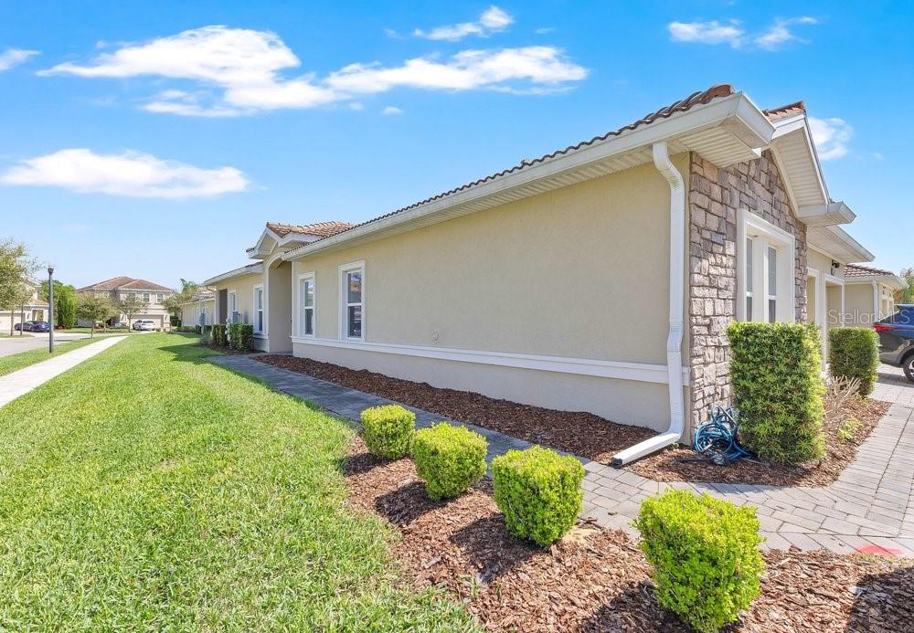 A side view of a beige stucco house with stone accents and a paved walkway — 1051 QUAKER RIDGE LANE, DAVENPORT, FL