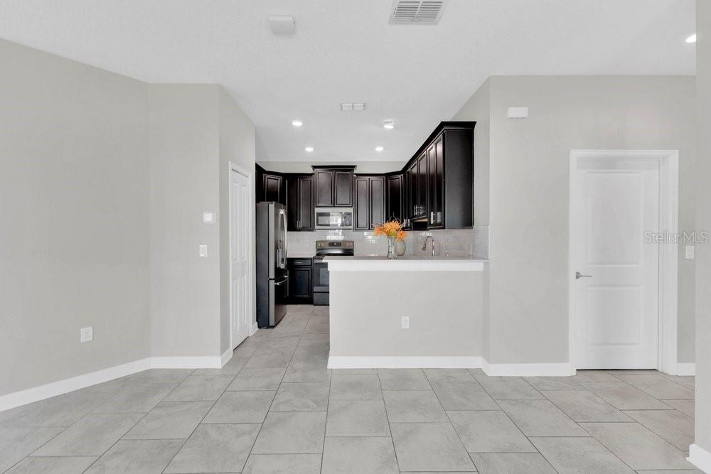A kitchen with dark cabinets, stainless steel appliances, and gray tile flooring — 1051 QUAKER RIDGE LANE, DAVENPORT, FL