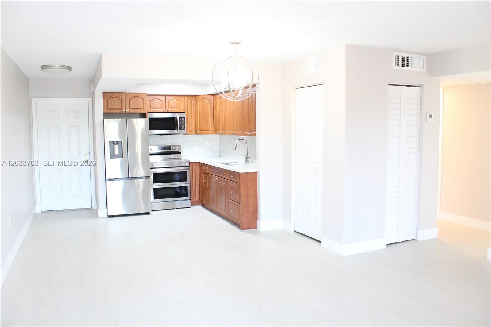 A kitchen features wood cabinets, stainless steel appliances, and white flooring in an open space — 6780 W 2nd Ct # 401, Hialeah FL 33012, HIALEAH, FL