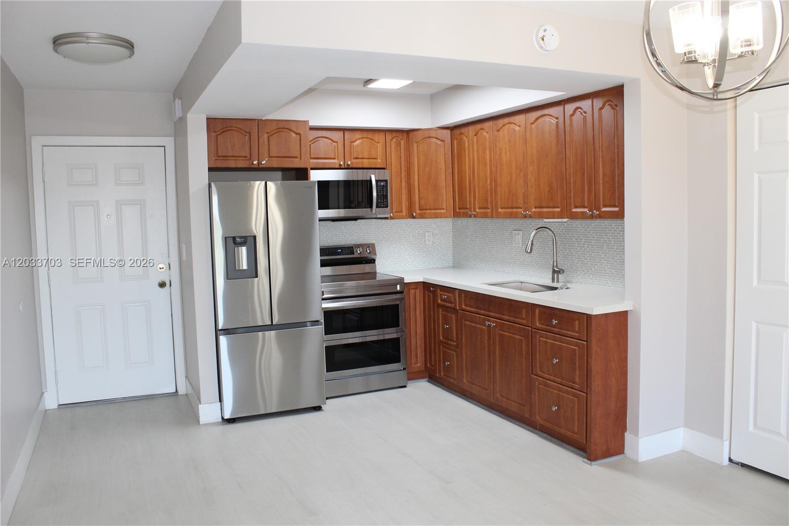 A kitchen features stainless steel appliances, wood cabinets, white countertops, and a light-colored floor — 6780 W 2nd Ct # 401, Hialeah FL 33012, HIALEAH, FL