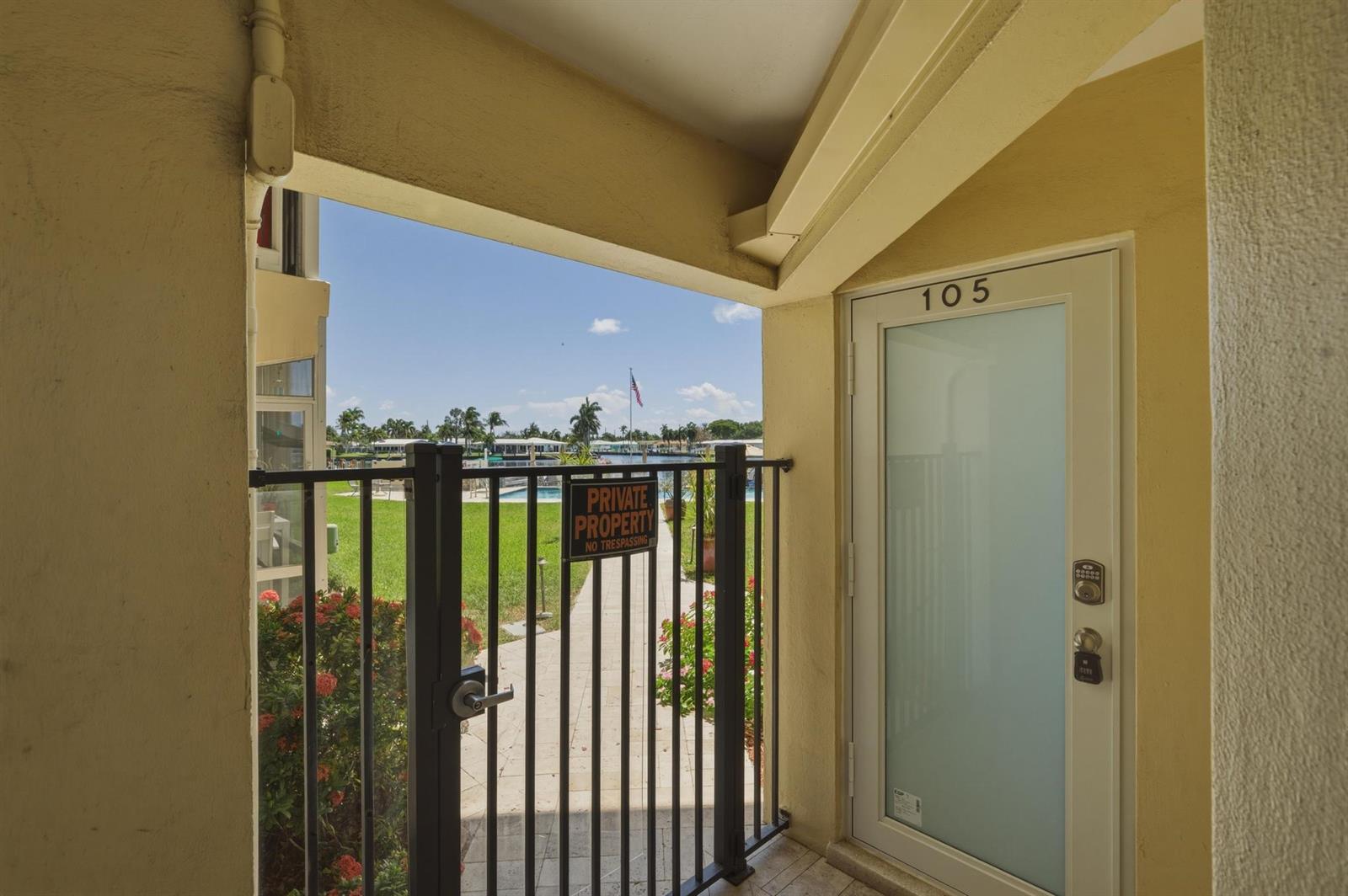 A view from a covered entryway toward a gated path and a waterfront area — 700 Pine Drive # 105, Pompano Beach FL 33060, POMPANO BEACH, FL