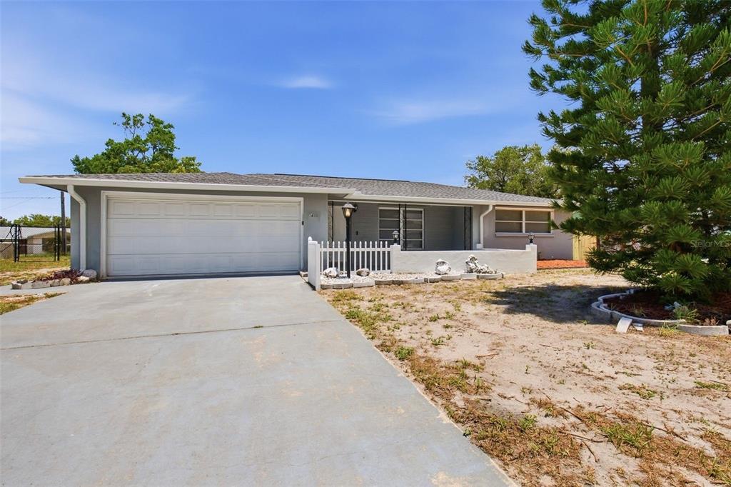 A single-story house with a gray exterior, a white garage door, and a front porch — 7617 JASMINE BOULEVARD, PORT RICHEY, FL