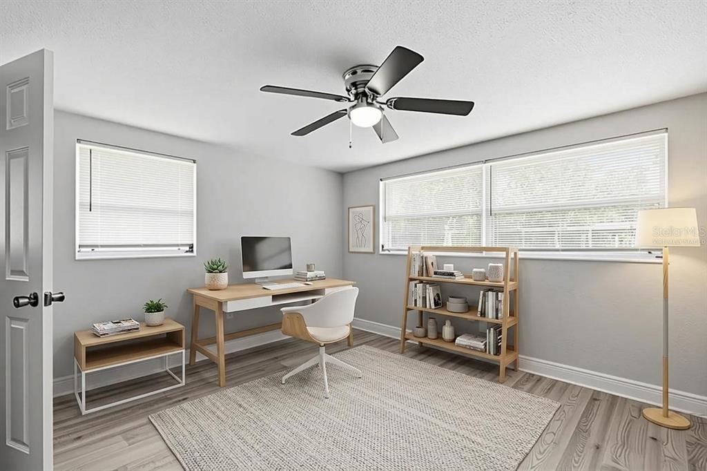A virtual staging rendering of a home office with a desk, chair, and bookshelf — 7617 JASMINE BOULEVARD, PORT RICHEY, FL