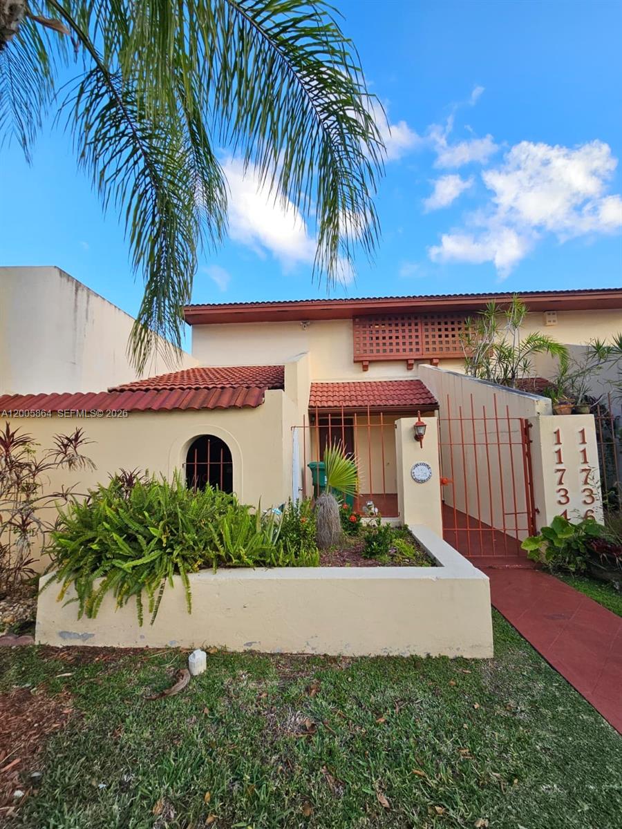 A beige two-story townhouse exterior features a red tile roof and a gated courtyard entrance — 11734 SW 112th Ln, Miami FL 33186, MIAMI, FL
