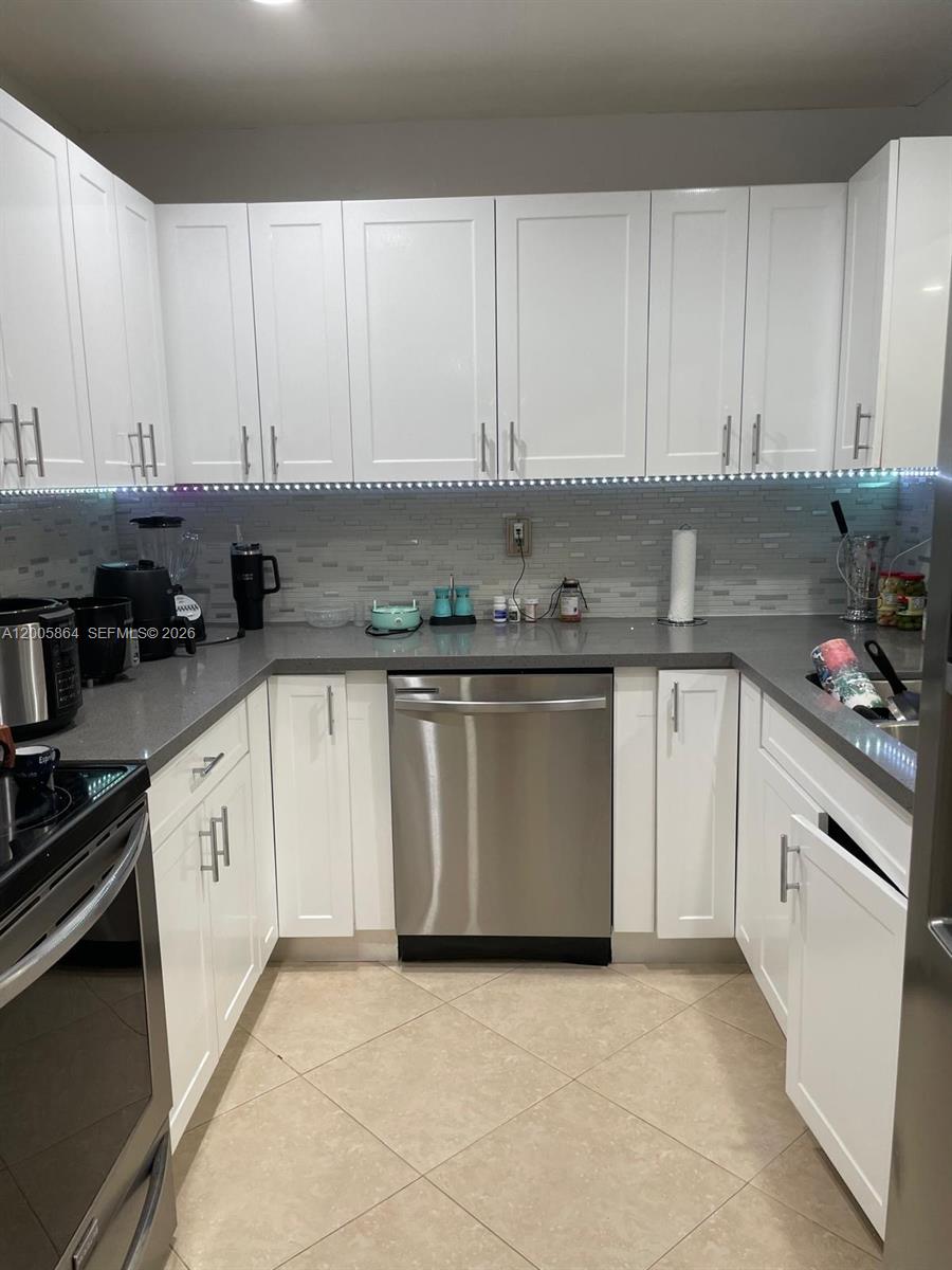 A kitchen features white cabinets, grey countertops, stainless steel appliances, and a tiled backsplash — 11734 SW 112th Ln, Miami FL 33186, MIAMI, FL