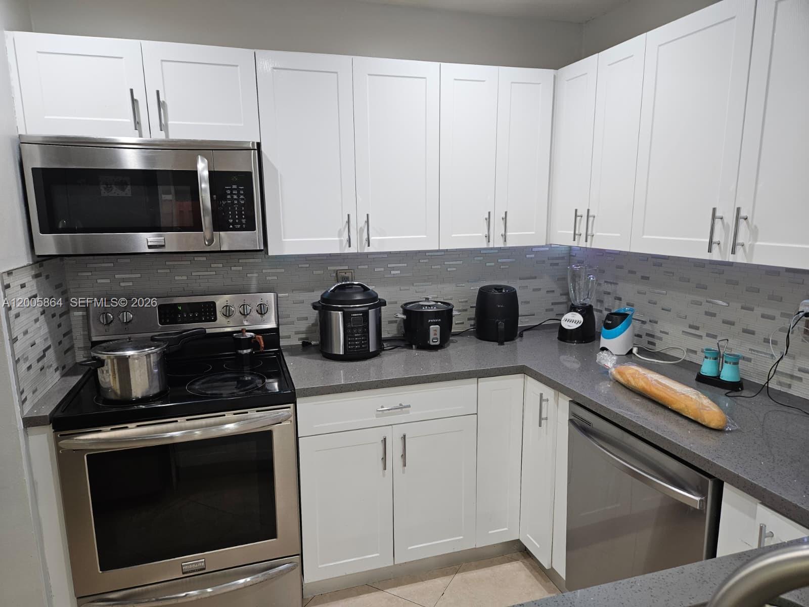 A kitchen features white cabinets, stainless steel appliances, gray countertops, and a gray tile backsplash — 11734 SW 112th Ln, Miami FL 33186, MIAMI, FL