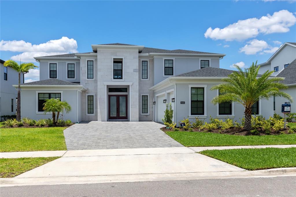 A two-story house with a stone facade, gray exterior, and a paved driveway — 9445 SANTORINI DRIVE, ORLANDO, FL