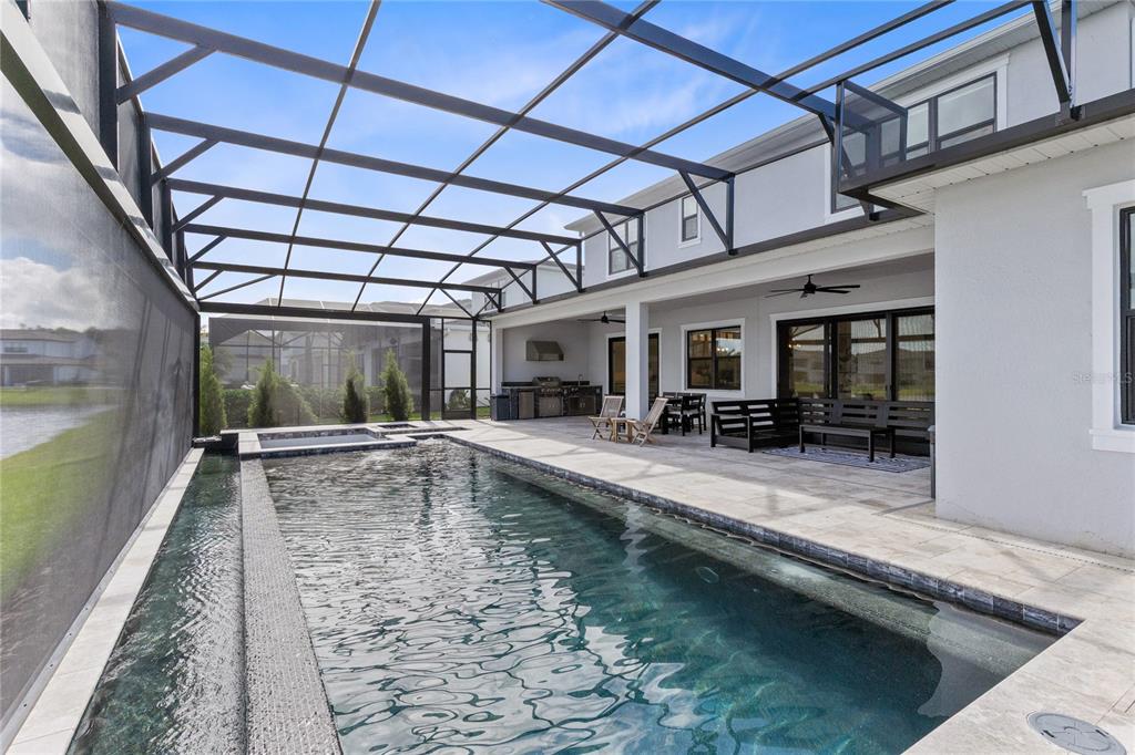 A screened-in patio features a rectangular swimming pool, a hot tub, and an outdoor kitchen — 9445 SANTORINI DRIVE, ORLANDO, FL