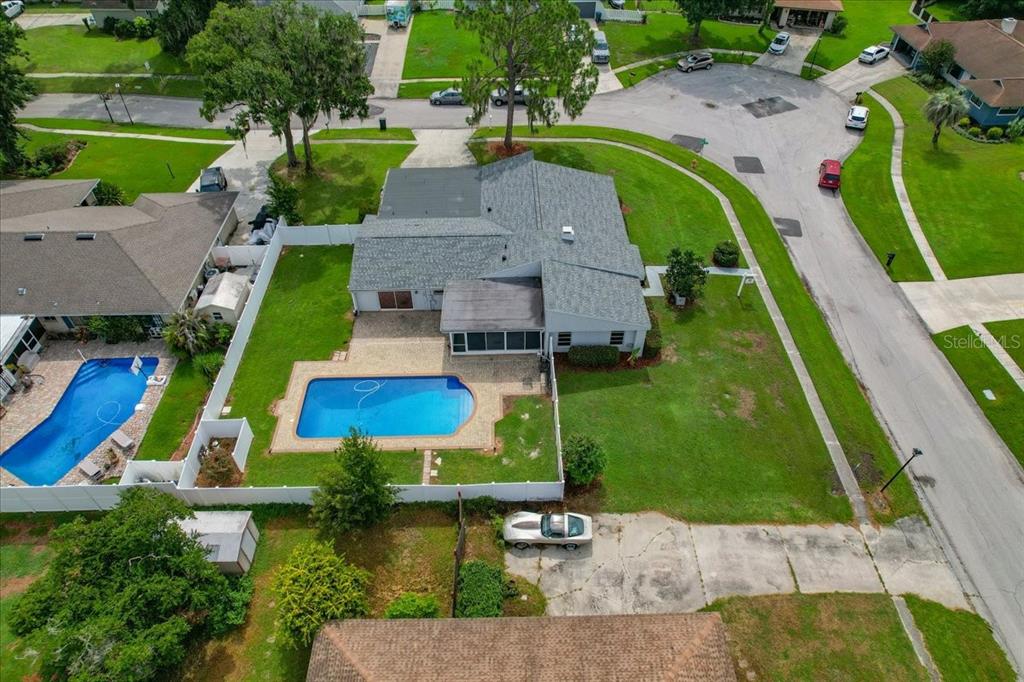 An aerial view shows a house with a swimming pool and a fenced backyard — 107 ELM SQUARE S, LAKELAND, FL