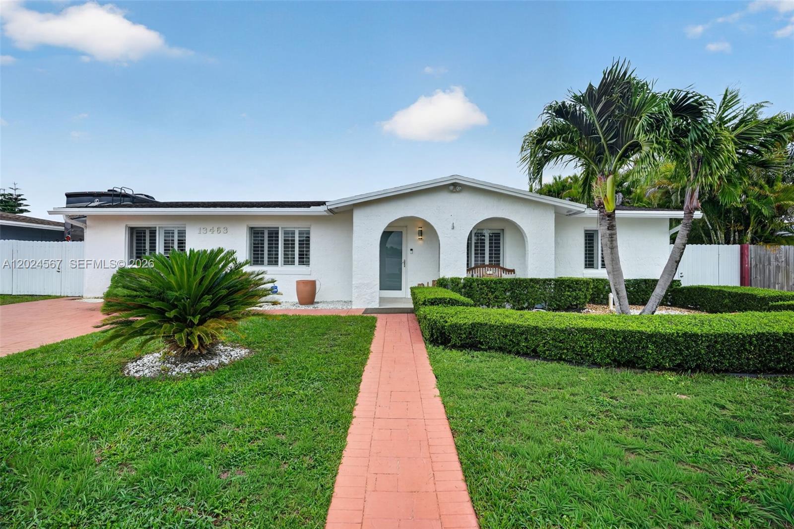 A white single-story house features a red brick walkway, manicured hedges, and palm trees — 13463 SW 66th Ter, Miami FL 33183, MIAMI, FL