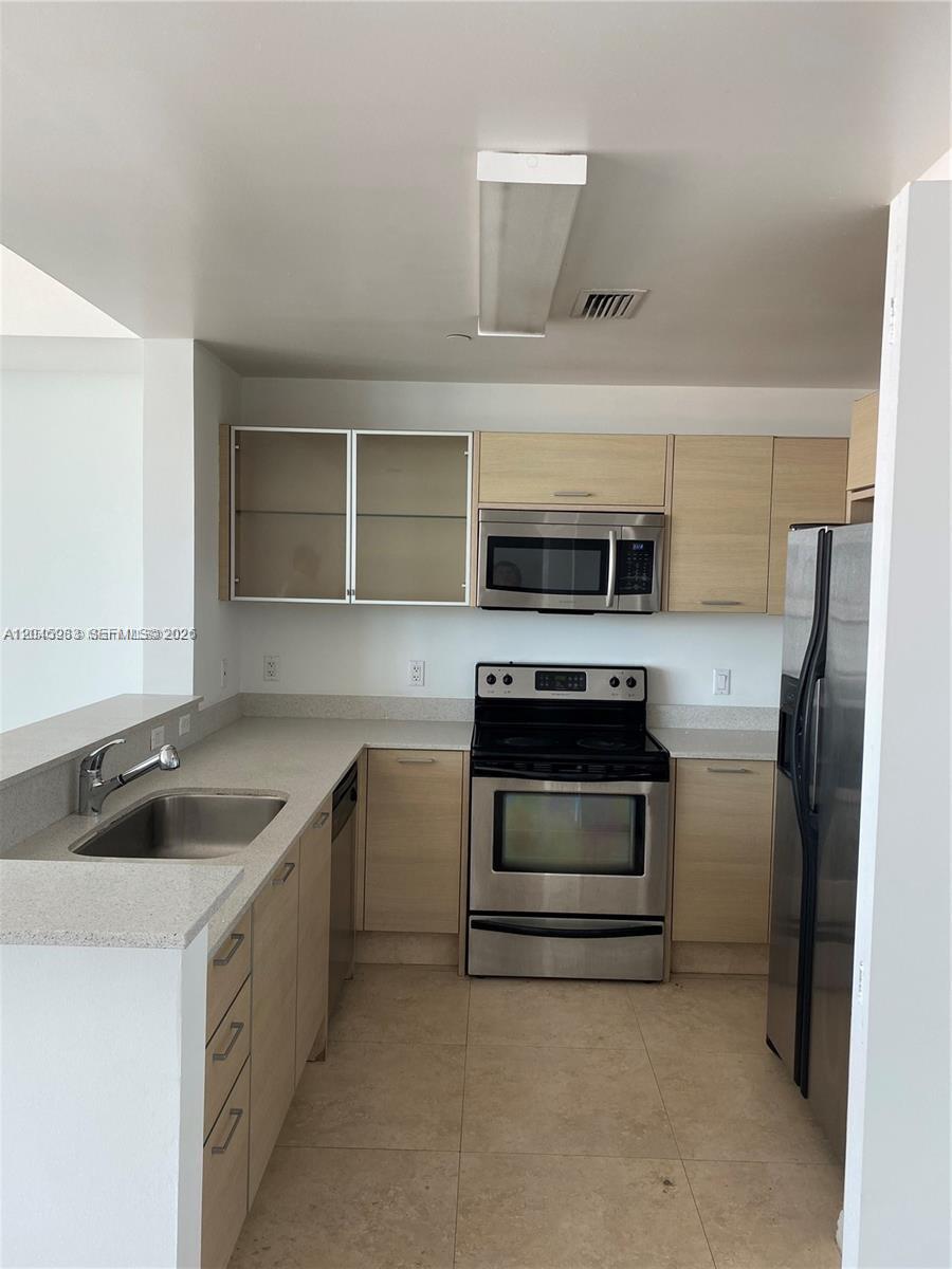 A kitchen features light wood cabinets, stainless steel appliances, and light-colored countertops — 350 NE 24th St # 813, Miami FL 33137, MIAMI, FL