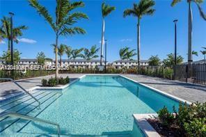 A rectangular swimming pool is surrounded by a paved deck, palm trees, and residential buildings — 4941 Peacock Way # 5838, Dania Beach FL 33312, DANIA BEACH, FL