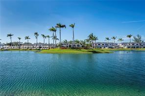 A view of a calm lake with palm trees and residential buildings in the background — 4941 Peacock Way # 5838, Dania Beach FL 33312, DANIA BEACH, FL