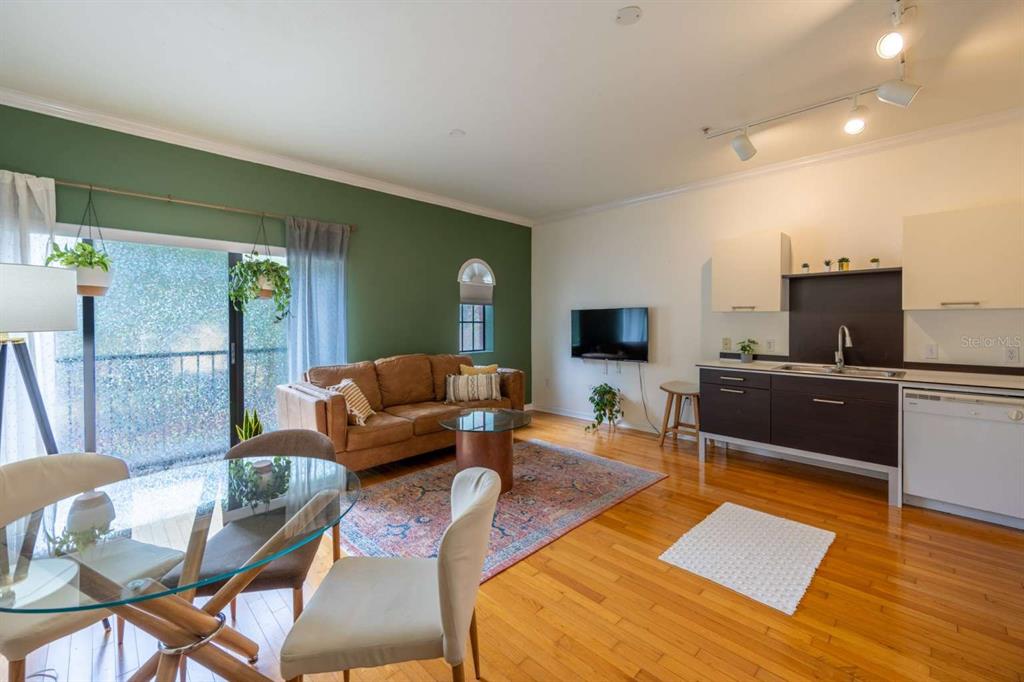 An open-concept living area features a kitchen, dining space, and a green accent wall — 20 SW 6TH STREET UNIT 211, GAINESVILLE, FL