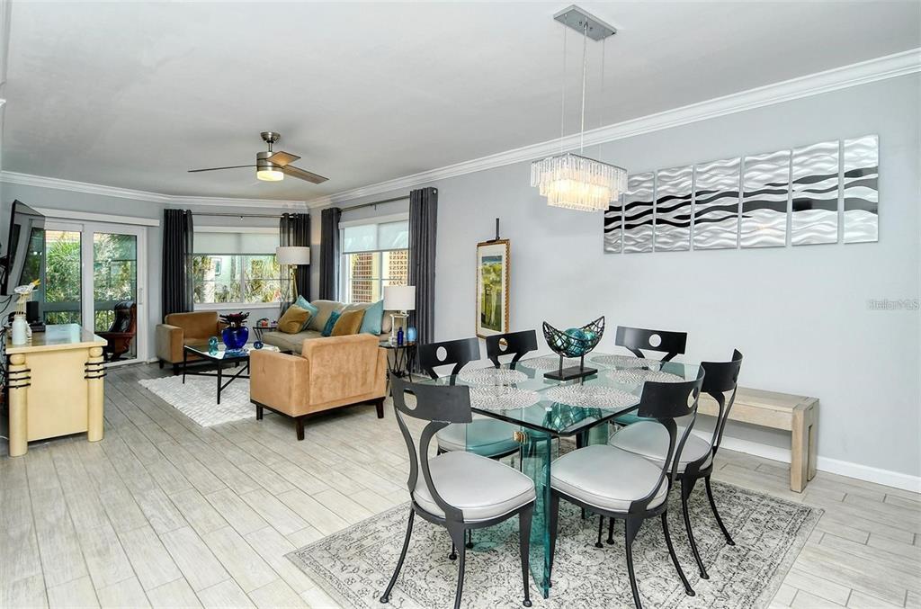 A bright, open-concept living and dining area features light tile flooring and modern furniture — 1215 S PORTOFINO DRIVE N UNIT 308, SARASOTA, FL
