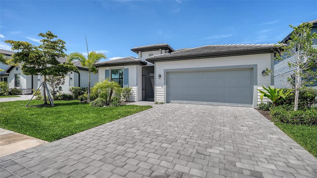 A single-story house with a gray garage door, white siding, and a paved driveway — 17233 MOONFLOWER DRIVE, VENICE, FL