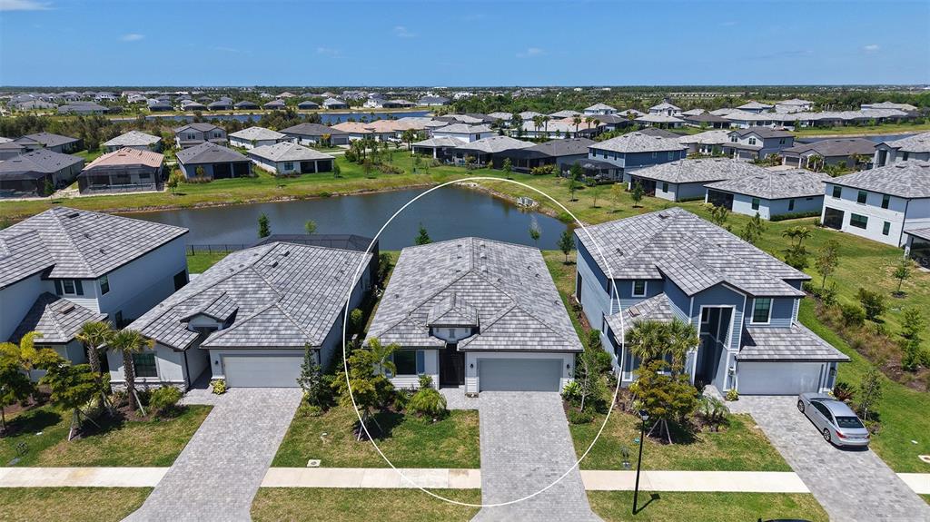 An aerial view of a single-story suburban house with a gray tiled roof and driveway — 17233 MOONFLOWER DRIVE, VENICE, FL