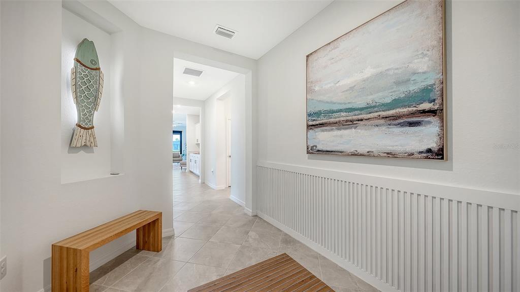 A hallway features a wooden bench, a fish wall sculpture, and a large abstract painting — 17233 MOONFLOWER DRIVE, VENICE, FL