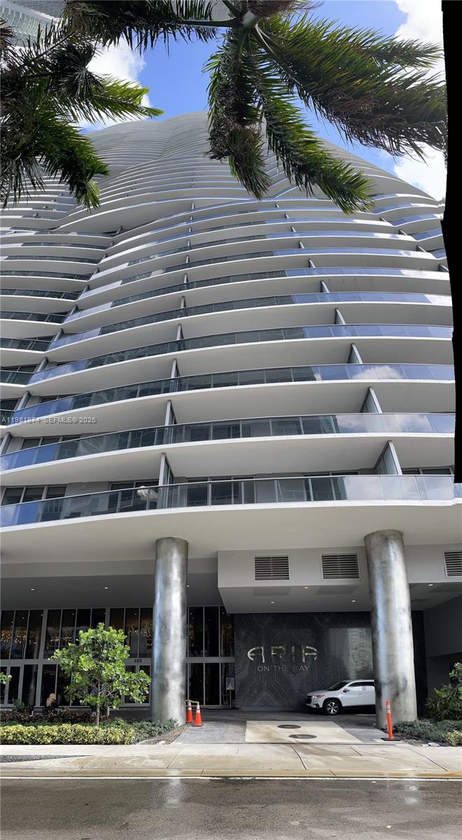 The exterior of a modern high-rise residential building features curved balconies and a ground-level entrance — 488 NE 18th St # 1000, Miami FL 33132, MIAMI, FL