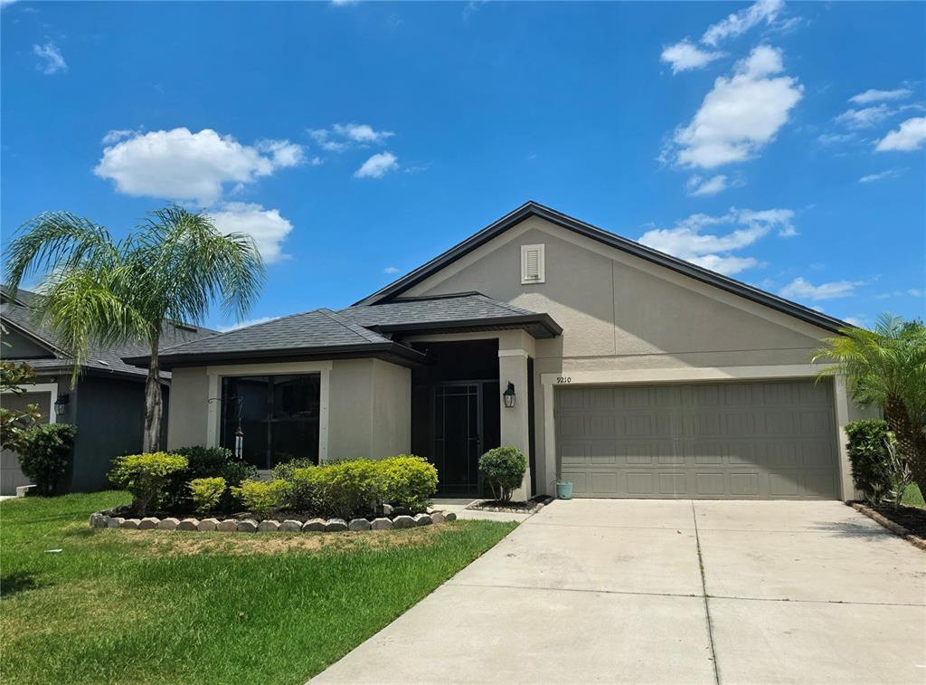 A single-story house with a beige stucco exterior, a two-car garage, and a front lawn — 9210 52ND AVENUE E, PALMETTO, FL