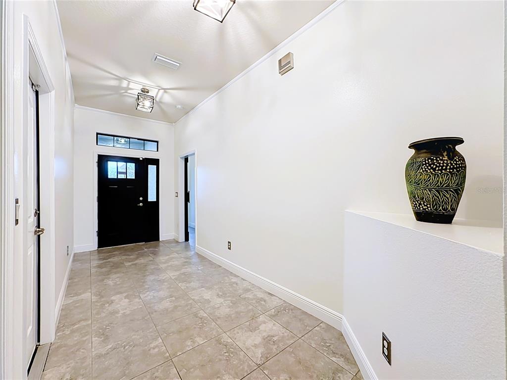 A tiled entryway features a black front door, white walls, and a decorative vase — 9210 52ND AVENUE E, PALMETTO, FL