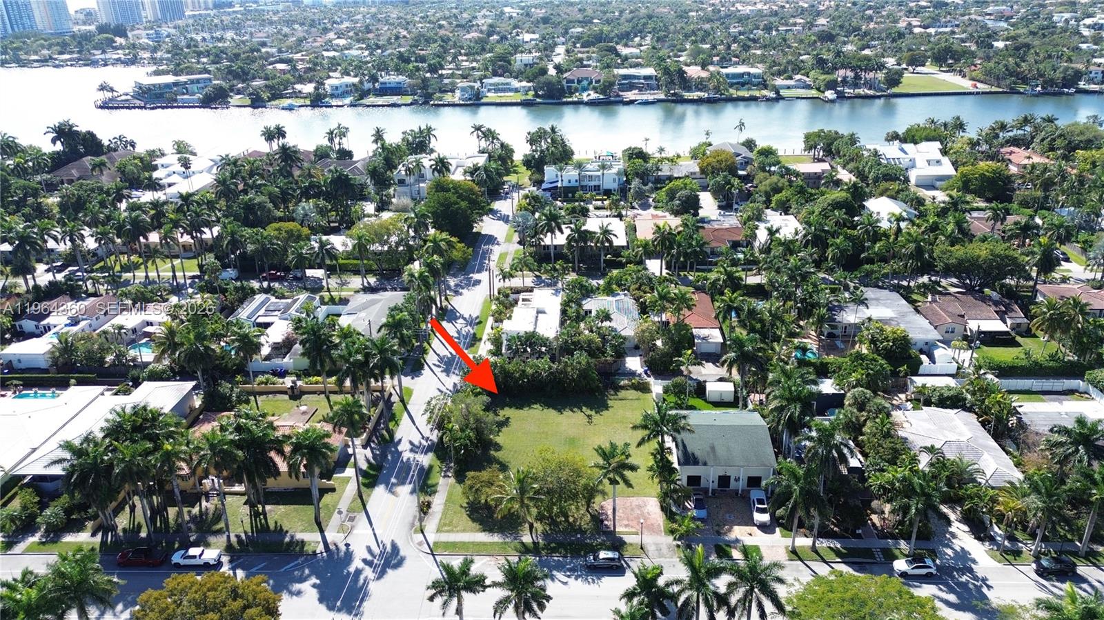 An aerial view shows a vacant, grassy residential lot situated between houses and palm trees — 1000 Harrison St, Hollywood FL 33019, HOLLYWOOD, FL