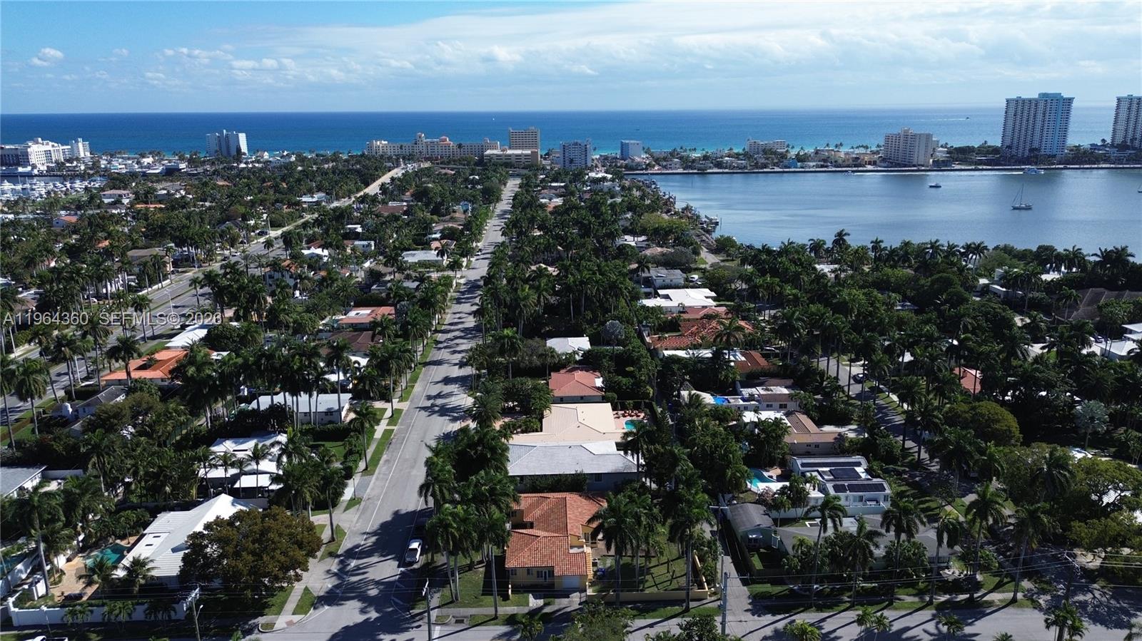 An aerial view shows a residential neighborhood with palm trees, houses, and a nearby bay — 1000 Harrison St, Hollywood FL 33019, HOLLYWOOD, FL