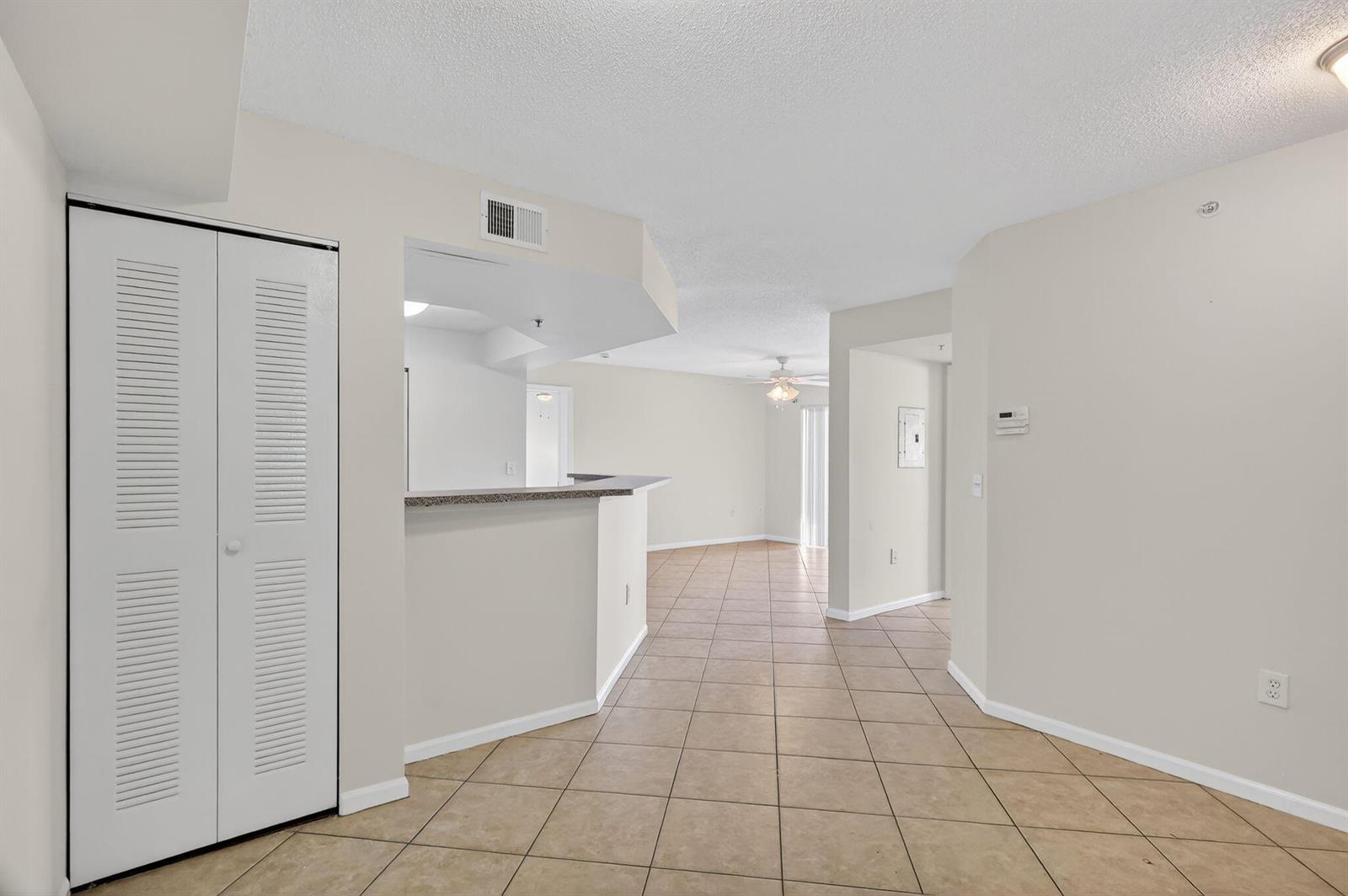 An interior view showing a tiled floor, a kitchen pass-through, and a white closet door — 3662 NW Adriatic Lane, Jensen Beach FL 34957, JENSEN BEACH, FL