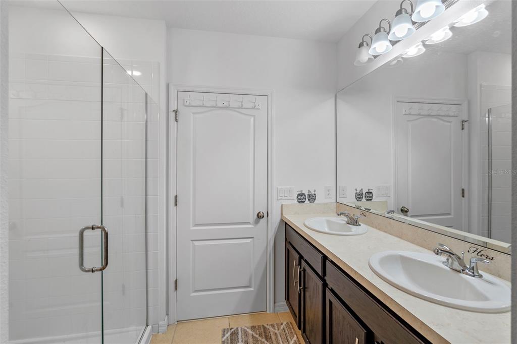 A bathroom features a glass-enclosed shower, a double vanity with dark cabinets, and white walls — 189 LUXMORE ROAD, GROVELAND, FL