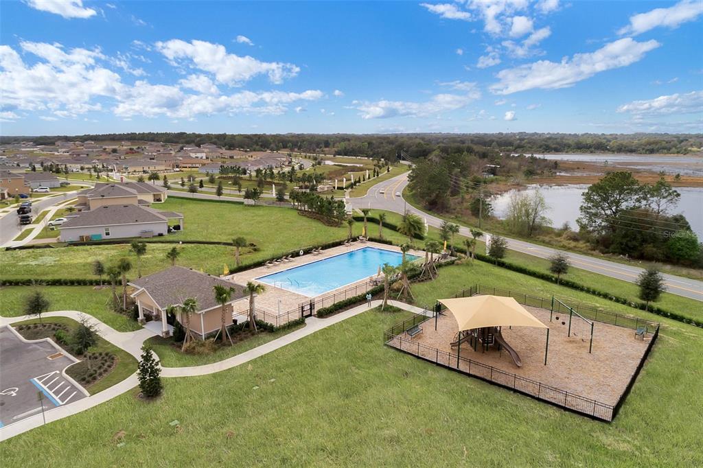 An aerial view shows a community swimming pool, a covered playground, and nearby residential homes — 189 LUXMORE ROAD, GROVELAND, FL