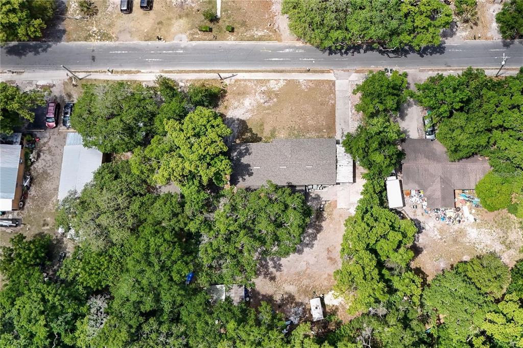 An aerial view shows a house with a gray roof surrounded by trees and dirt — 1400 N SIMPSON STREET, MOUNT DORA, FL