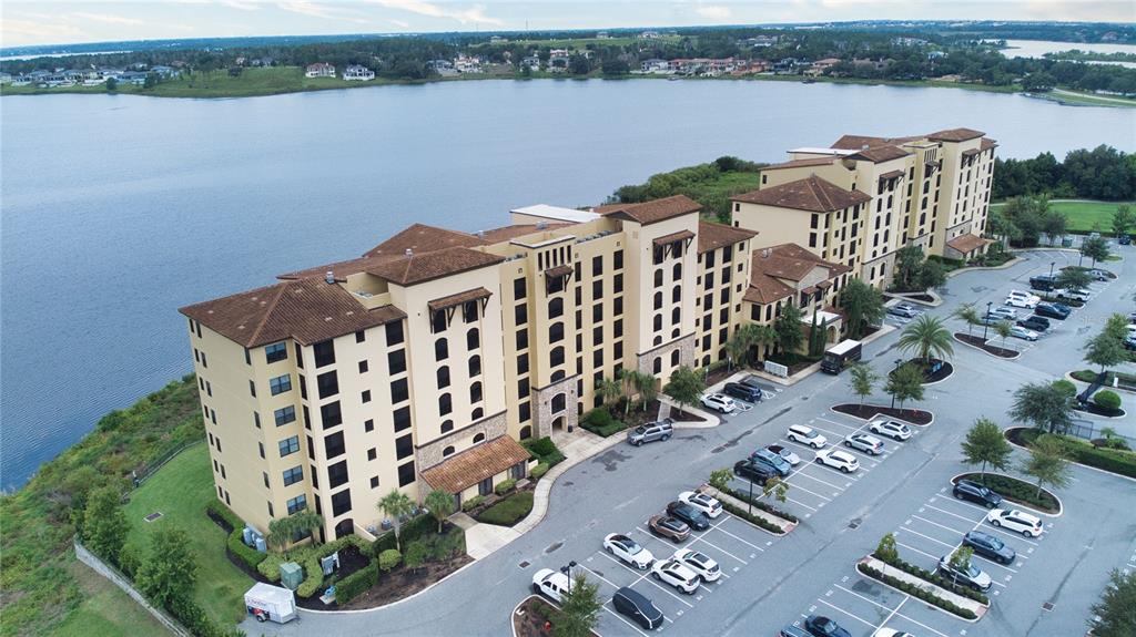 An aerial view shows a multi-story apartment building situated next to a large lake — 16300 COUNTY ROAD 455 UNIT 307, MONTVERDE, FL