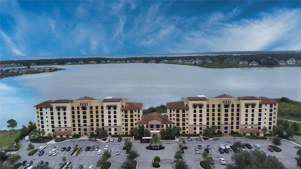 An aerial view of a large multi-story apartment complex situated beside a wide lake — 16300 COUNTY ROAD 455 UNIT 307, MONTVERDE, FL