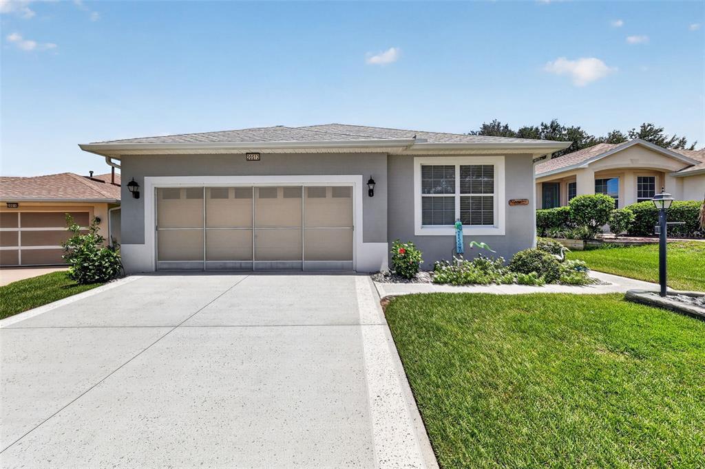 A gray single-story house with a two-car garage and a concrete driveway — 20512 QUEEN ALEXANDRA DRIVE, LEESBURG, FL