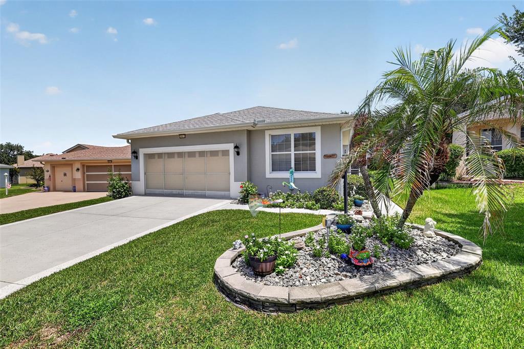 A single-story house with a gray exterior, a two-car garage, and a landscaped front garden — 20512 QUEEN ALEXANDRA DRIVE, LEESBURG, FL