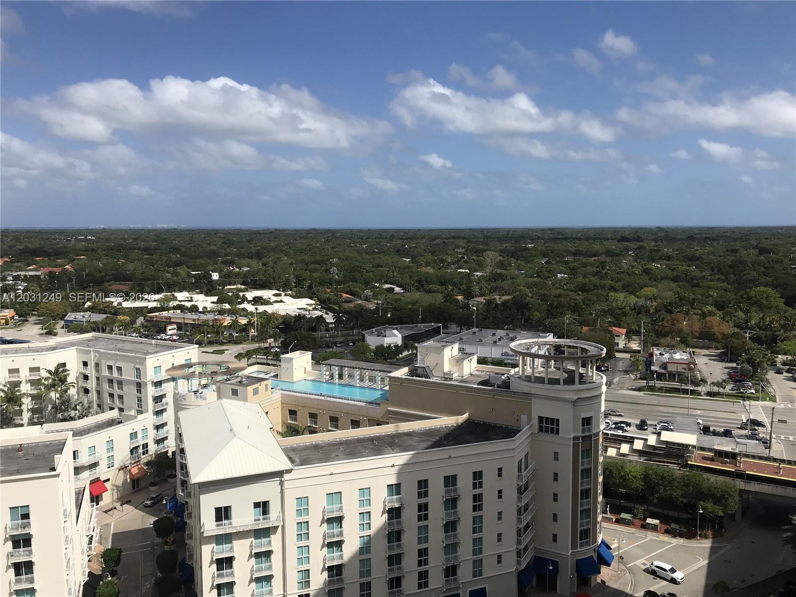 An elevated exterior view shows a multi-story apartment complex with a rooftop pool — 9055 SW 73rd Ct # 1604, Miami FL 33156, MIAMI, FL
