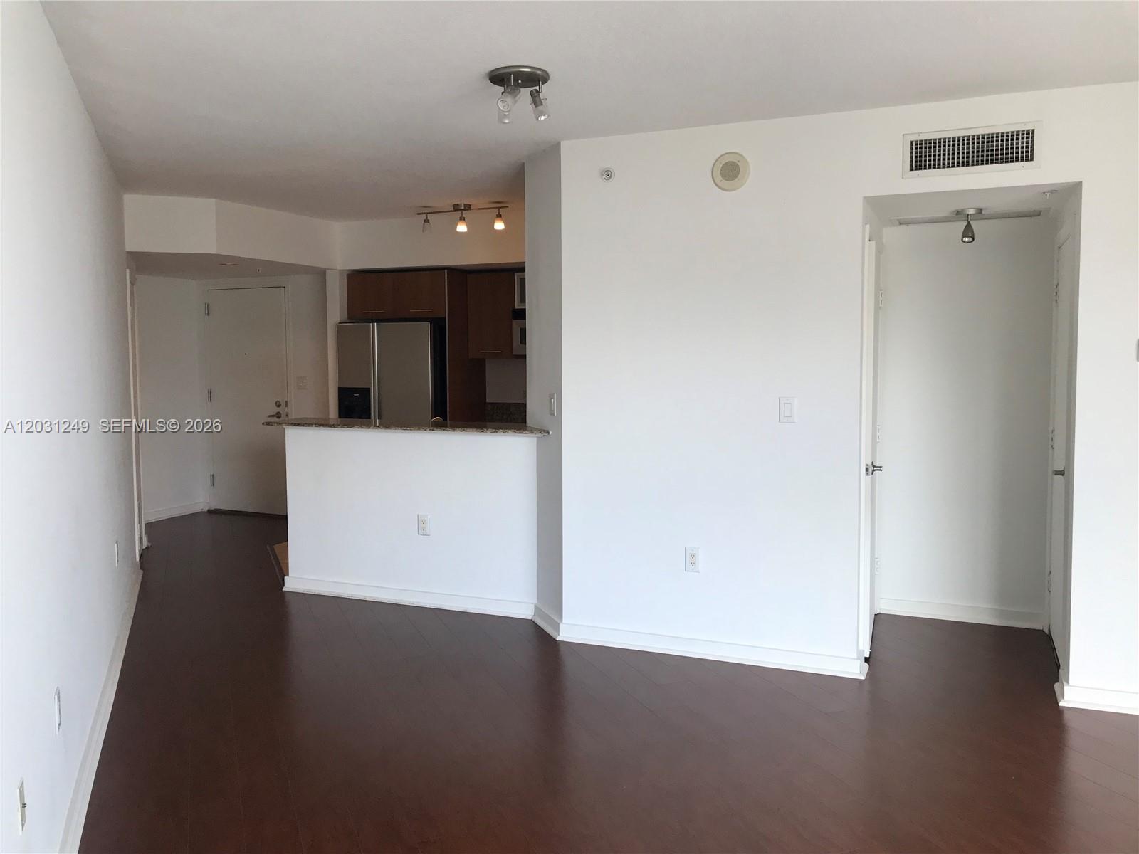 An interior view shows a kitchen with a breakfast bar, dark flooring, and white walls — 9055 SW 73rd Ct # 1604, Miami FL 33156, MIAMI, FL