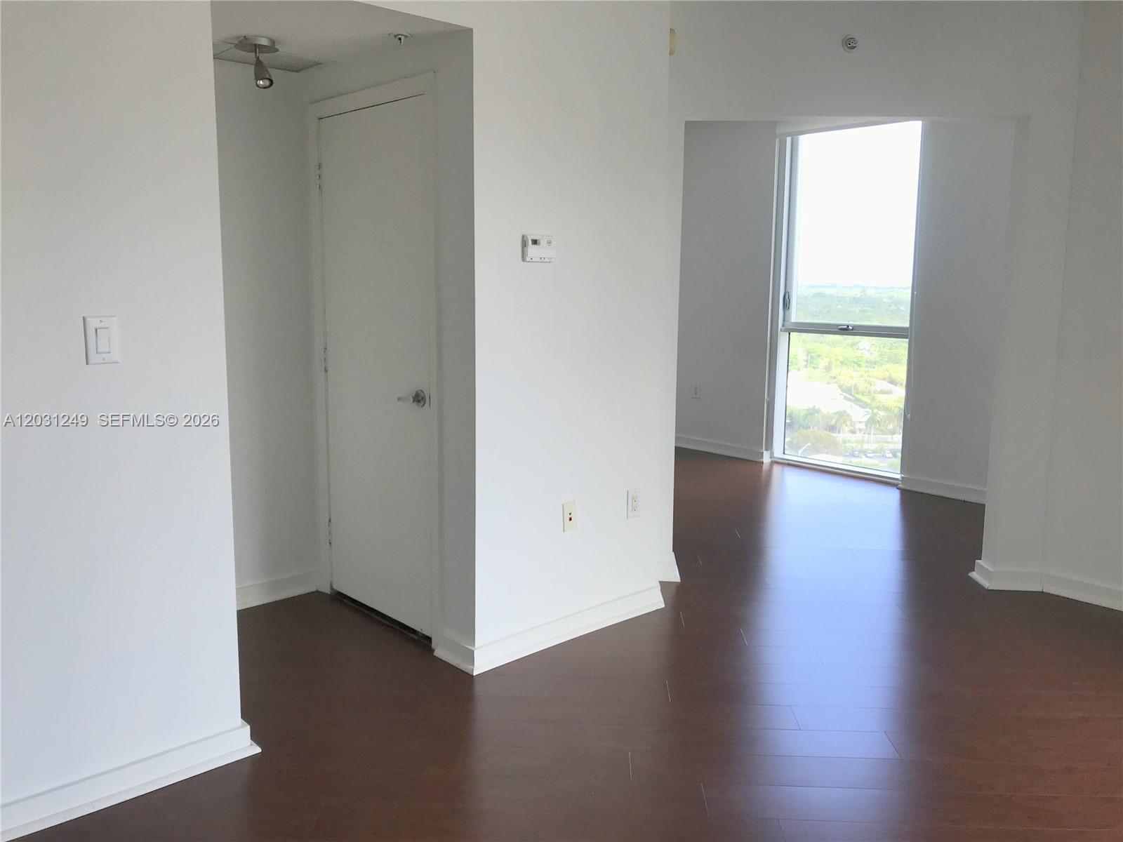 An interior view shows a room with dark wood flooring, white walls, and a large window — 9055 SW 73rd Ct # 1604, Miami FL 33156, MIAMI, FL